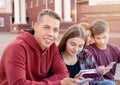 Happy smiling teenage boy and girl checking his phone against a group of students on the stairs near university Royalty Free Stock Photo