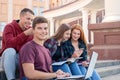 Happy smiling teenage boy with notebook against a group of students on the stairs near university Royalty Free Stock Photo