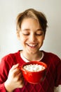 Happy smiling teenager boy holding a red cup with cocoa and marshmallows. Soft selective focus.