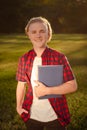 happy smiling teenager boy with notebook in hands stand on school yard or park in sunny day Royalty Free Stock Photo