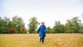 Happy smiling toddler boy in jacket running on field with dry grass on cloudy autumn day Royalty Free Stock Photo