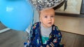 Happy smiling toddler boy sitting on floor and playing with colorful air balloons on his first birthday party Royalty Free Stock Photo