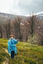 Happy smiling traveller senior beautiful woman in blue rain jacket and jeans in mountains surrounded by forest, enjoying Royalty Free Stock Photo