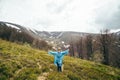 Happy smiling traveller senior beautiful woman in blue rain jacket and jeans in mountains surrounded by forest, enjoying Royalty Free Stock Photo