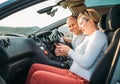 Happy smiling two young adulds couple using smartphone navigation inside car during auto jorney.They are laughing during road trip