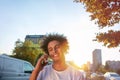 Happy smiling urban hipster young man using smart phone. African american teenager holding mobile smartphone on sunset Royalty Free Stock Photo