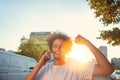 Happy smiling urban hipster young man using smart phone. African american teenager holding mobile smartphone on sunset Royalty Free Stock Photo