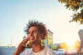 Happy smiling urban hipster young man using smart phone. African american teenager holding mobile smartphone on sunset Royalty Free Stock Photo