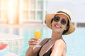 Happy smiling woman in bikini with straw hat relaxing with orange juice at poolside. beautiful female relaxing in summer time. Royalty Free Stock Photo