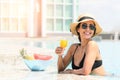 Happy smiling woman in bikini with straw hat relaxing with orange juice at poolside. beautiful female relaxing in summer time. Royalty Free Stock Photo