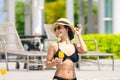 Happy smiling woman in bikini with straw hat relaxing with orange juice at poolside. beautiful female relaxing in summer time. Royalty Free Stock Photo