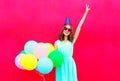 Happy smiling woman in a birthday cap having fun over an air colorful balloons pink Royalty Free Stock Photo