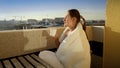 Happy smiling woman drinking coffee on balcony and enjoying morning sun. People in morning, relaxing at home, enjoying city view Royalty Free Stock Photo