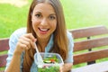 Happy smiling woman eating salad sitting in the park looks at camera with copy space area. Lunch salad take out container healthy Royalty Free Stock Photo