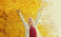 Happy smiling woman flying yellow leaves in autumn park