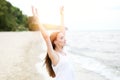 Happy smiling woman in free happiness bliss on ocean beach standing with raising hands. Portrait of a multicultural