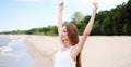 Happy smiling woman in free happiness bliss on ocean beach standing with raising hands. Portrait of a multicultural