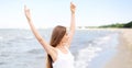 Happy smiling woman in free happiness bliss on ocean beach standing with raising hands. Portrait of a multicultural