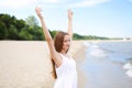 Happy smiling woman in free happiness bliss on ocean beach standing with raising hands. Portrait of a multicultural