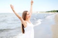 Happy smiling woman in free happiness bliss on ocean beach standing with raising hands. Portrait of a multicultural