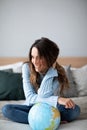 Happy smiling woman with a globe on bed