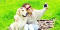 Happy smiling woman with Golden Retriever dog taking selfie picture by phone in summer Royalty Free Stock Photo