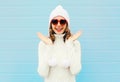 Happy smiling woman having fun wearing a heart shape sunglasses, knitted hat, sweater over blue Royalty Free Stock Photo