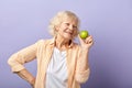 Happy smiling woman in her sixties holding green apple and smiling at camera.