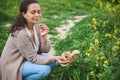 Happy smiling woman sniffing flower while picking medicinal herbs in the meadow for aromatherapy or preparing herbal tea