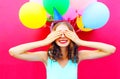 Happy smiling woman is hides her eyes with hands having fun over an air colorful balloons pink Royalty Free Stock Photo