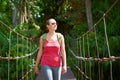 Happy smiling woman hiker crossing suspension bridge in sunlight Royalty Free Stock Photo