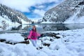 Happy smiling woman hiking snowshoeing in snow covered trail by calm alpine lake with reflections of mountains and trees
