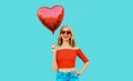 happy smiling woman holding red heart shaped air balloon on colorful blue Royalty Free Stock Photo