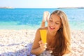 Happy smiling woman holding sun cream tube protection lying on pebbles beach. Sunscreen girl looking suntan lotion in plastic Royalty Free Stock Photo