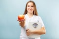 Happy smiling woman holding weight scales and red apple on blue background Royalty Free Stock Photo