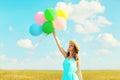 Happy smiling woman holds an air colorful balloons is enjoying a summer day on meadow blue sky Royalty Free Stock Photo