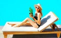 happy smiling woman lies on deckchair with pineapple over blue water pool background Royalty Free Stock Photo