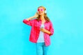 Happy smiling woman listens to music in a wireless headphones with smartphone in pink denim jacket