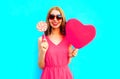 Happy smiling woman with lollipop, pink heart shaped air balloons on colorful blue Royalty Free Stock Photo