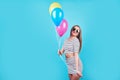 Happy smiling woman is looking on an air colorful balloons having fun over a blue background Royalty Free Stock Photo