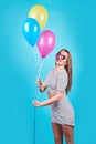 Happy smiling woman is looking on an air colorful balloons having fun over a blue background Royalty Free Stock Photo