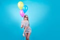 Happy smiling woman is looking on an air colorful balloons having fun over a blue background Royalty Free Stock Photo