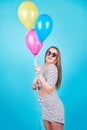 Happy smiling woman is looking on an air colorful balloons having fun over a blue background Royalty Free Stock Photo