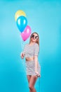 Happy smiling woman is looking on an air colorful balloons having fun over a blue background Royalty Free Stock Photo