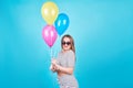 Happy smiling woman is looking on an air colorful balloons having fun over a blue background Royalty Free Stock Photo