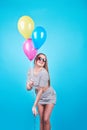 Happy smiling woman is looking on an air colorful balloons having fun over a blue background Royalty Free Stock Photo