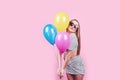 Happy smiling woman is looking on an air colorful balloons having fun over a pink background Royalty Free Stock Photo