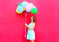 Happy smiling woman is looking on an air colorful balloons having fun over pink background Royalty Free Stock Photo