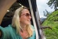 Happy smiling woman looks out from window traveling by train on most picturesque train road in Sri Lanka Royalty Free Stock Photo