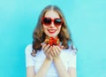 Happy smiling woman with many strawberry over blue